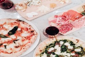A table full of pizzas and wine on a marble table.